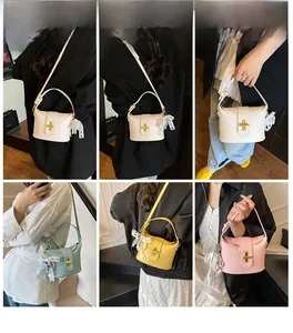 Detail view of lychee pattern leather bucket bag with gold twist lock and pearl pendant