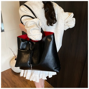 Close-up of black textured leather tote with red lining and a mini zipper pouch attachment