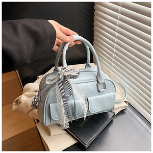 Gros plan sur un sac Boston bleu clair vintage avec nœud en dentelle et deux poches