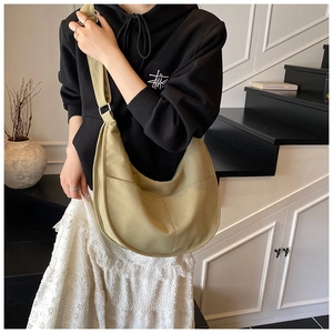 Detailed shot of an olive green canvas hobo bag with wide strap on a model