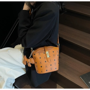 Detail shot of brown bucket bag with teddy bear pattern and metallic buckle on wooden stairs
