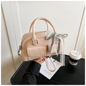 Détail du sac Boston en cuir rose avec texture litchi et accessoire nœud en dentelle