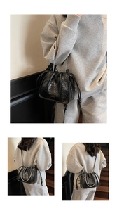 Detail of black woven leather bucket bag with silver chain strap and drawstring closure