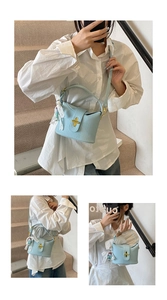Detail of light blue pebble leather handbag with gold bar lock and astronaut charm decoration