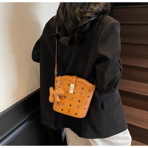 Brown bucket bag with bear monogram print and dog charm shown on a female model