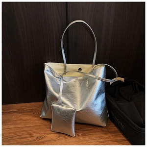 Detail view of metallic silver tote bag with crinkled faux leather texture and mini pouch