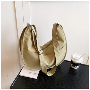 Detail of avocado green crescent bag with adjustable strap and side pocket in casual setting