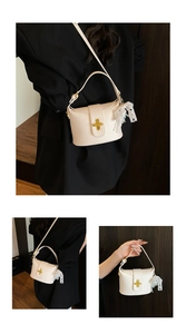 Detailed macro view of beige pebble leather handbag featuring a gold cross-shaped twist lock