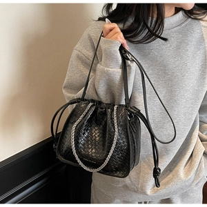 Close-up of black woven texture bucket bag with silver chain and drawstring detail
