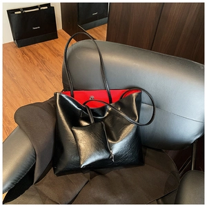 Close-up of black patent leather tote bag with vibrant red interior and magnetic closure