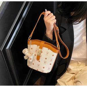 Detail of printed bucket bag featuring gold twist lock and cute animal charm accessory