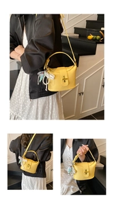 Close-up of yellow lychee texture bucket bag with gold clasp and pearl lace charm