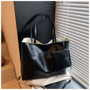 Close-up of black leather tote bag featuring dual handles and a detachable small pouch