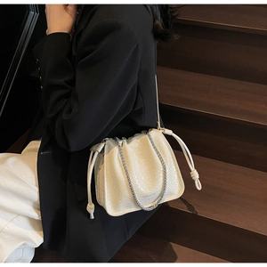 Detail of woven texture and drawstring closure on creamy white faux leather bucket bag