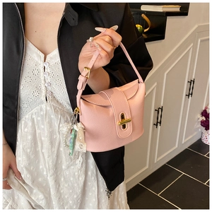 Detail of pink lychee texture bucket bag with gold twist lock and lace pendant