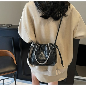 Detail of black woven bucket bag showing silver chain handle and drawstring closure