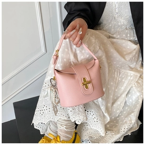 Detail of pink lychee leather bucket bag with pearl charm and gold turn-lock closure