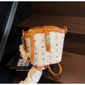 Detailed shot of beige bucket bag with bear print and leather strap on wooden stairs