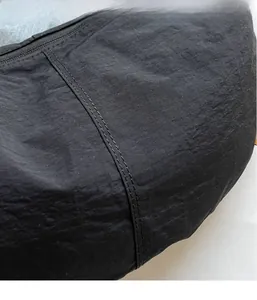 Close-up of black lightweight nylon fabric with detailed stitching and smooth zipper