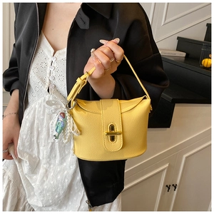 Detail of yellow lychee texture bucket bag with gold twist lock and pearl pendant charm