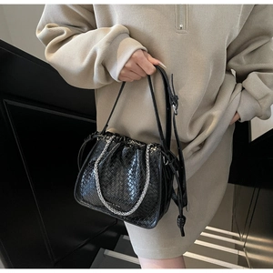Detail of black woven leather bucket bag with silver chain and drawstring closure
