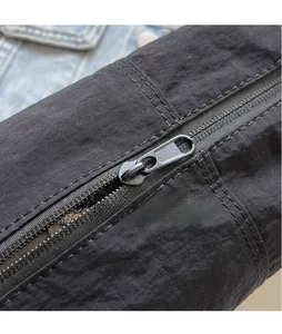 Detailed close-up of the smooth metal zipper and black nylon fabric texture on this crossbody bag