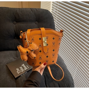 Detail of caramel lychee leather bucket bag with bear print and cute dog charm attachment