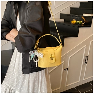 Close-up of bright yellow litchi pattern bucket bag with golden turn-lock and pearl charm