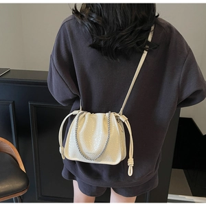 Close-up of the woven texture and silver chain strap on this creamy white bucket bag