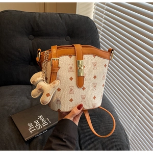 Close-up of cream bucket bag with teddy bear print and brown leather trim details