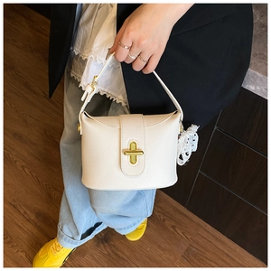 Close-up of cream white lychee leather bucket bag with gold lock and lace charm