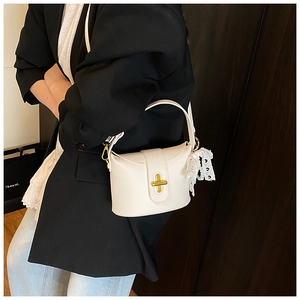 Detail of off-white lychee leather bucket bag with gold cross-lock and lace bow charm