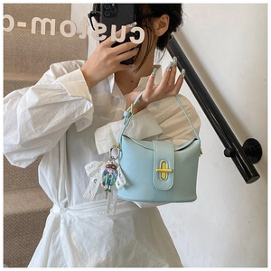 Detail of light blue lychee pattern bucket bag with gold lock and lace bow charm