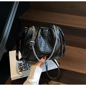 Detailed view of black woven bucket bag with silver chain and drawstring closure