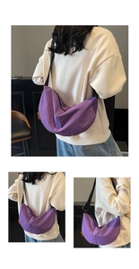 Detail showing purple nylon crescent bag with adjustable black strap and orange brand tag