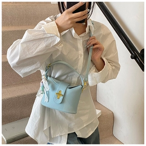 Detail of light blue lychee pattern leather bucket bag with gold lock and lace bow charm