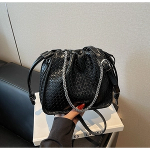 Close-up of black woven bucket bag with silver chain and drawstring texture detail