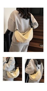 Detail view of cream dumpling bag showing orange logo tag and adjustable black strap