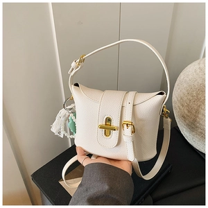 Close-up of white lychee pattern bucket bag with golden cross lock and pearl floral charm