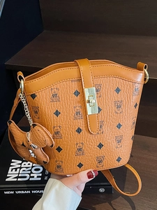 Classic brown bucket bag with teddy bear pattern and leather charm in lifestyle setting