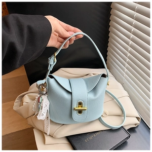 Close-up of light blue lychee pattern leather bucket bag with gold lock and pearl charm