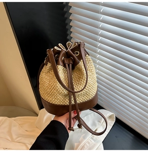 Detailed view of color-block straw bucket bag featuring leather drawstring and fine weaving