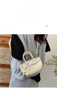 Detail of off-white lychee texture handbag with silver clasp and pearl heart charm