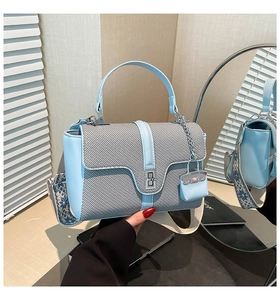 Detail der blauen Handtasche mit silbernem Drehverschluss und breitem Blumen-Schultergurt