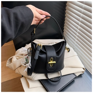 Detail of lychee pattern leather bucket bag with gold lock and pearl lace charm
