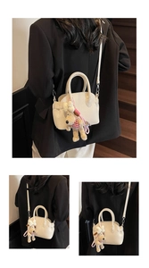 Detail of cream lychee texture shell bag with a cute cartoon puppy pendant accessory