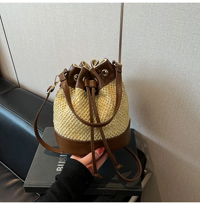 Detail view of the contrast straw bucket bag featuring dark brown leather drawstring closure