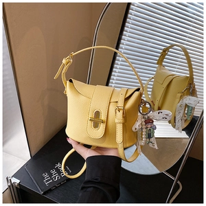 Close-up of yellow lychee pattern leather bucket bag with gold lock and pearl charm detail