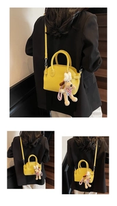Detail of yellow litchi leather mini bag with a cute puppy plush charm on a staircase