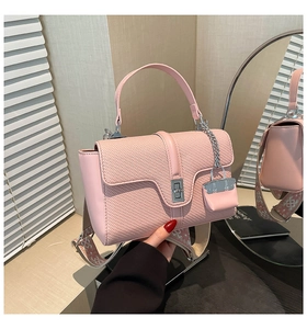Detail der rosa PU-Handtasche mit Webstruktur, Drehverschluss und Jacquard-Schultergurt